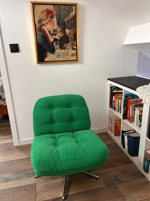 a green chair in a room with a book shelf at Apartement La Cuverie in Carcassonne