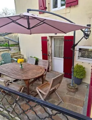 a wooden table and chairs under an umbrella at My Agradi, Maison de village in Les Martys