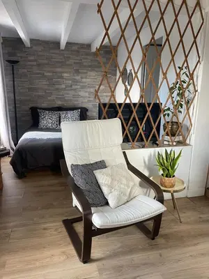 a living room with a chair and a bed at Logement Idéal pour un couple in Puisserguier