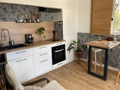 a kitchen with white cabinets and a sink and a table at Logement Idéal pour un couple in Puisserguier