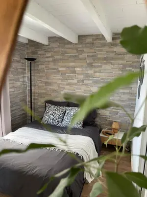 a bedroom with a brick wall and a bed at Logement Idéal pour un couple in Puisserguier