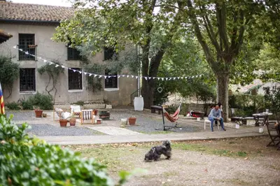 a woman sitting in a chair in a yard with a dog at Domaine Castelnaut gîte et château in Laroque-de-Fa