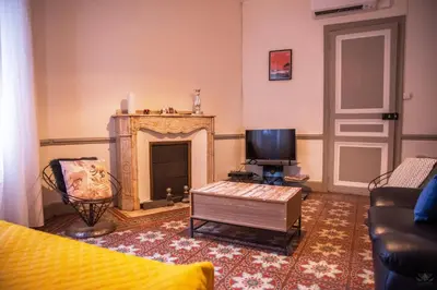 a bedroom with two beds and a window and a table at Les Tomettes du Midi - Élégance & Authenticité in Carcassonne