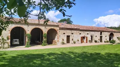 a bedroom with a large bed and a desk at Chambres et appartement de charme dans ferme de caractère - billard, jardin et cheminée - près du Canal du Midi in Lagarde