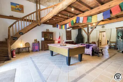 a fireplace in a living room with a table and wine glasses at Chambres et appartement de charme dans ferme de caractère - billard, jardin et cheminée - près du Canal du Midi in Lagarde