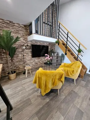a living room with a fireplace and a yellow blanket at Le Nid de Moline 3 étoiles in Villemoustaussou