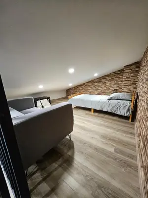 a bedroom with two beds and a brick wall at Le Nid de Moline 3 étoiles in Villemoustaussou