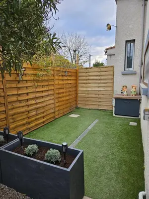 a backyard with a wooden fence and green grass at Le Nid de Moline 3 étoiles in Villemoustaussou