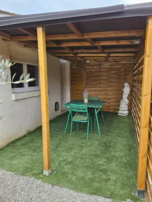 a patio with a green table in a house at Le Nid de Moline 3 étoiles in Villemoustaussou
