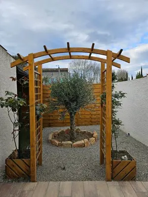 a wooden arch with a tree in a garden at Le Nid de Moline 3 étoiles in Villemoustaussou
