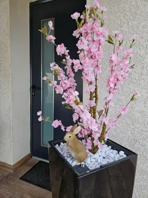 a rabbit sitting next to a tree with pink flowers at Le Nid de Moline 3 étoiles in Villemoustaussou