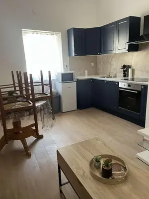 a kitchen with blue cabinets and a table and chairs at Appartement douzens in Douzens