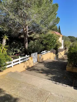 a white fence and a tree in a yard at Location maison vacances T3 in Gruissan