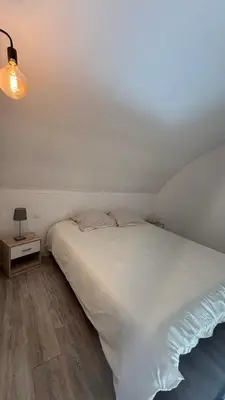 a bedroom with a white bed and a night stand at Location maison vacances T3 in Gruissan