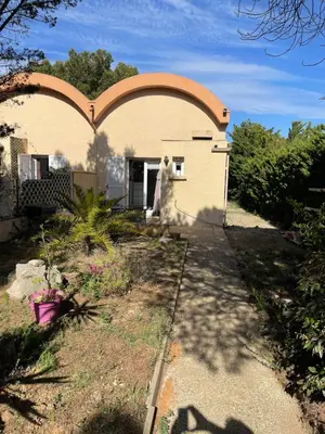 a dog standing in front of a building with an arch at Location maison vacances T3 in Gruissan