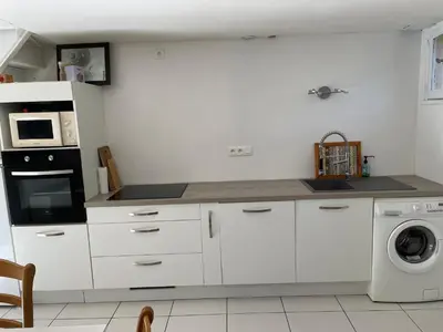 a kitchen with white cabinets and a washer and dryer at Location maison vacances T3 in Gruissan