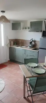 a kitchen with green cabinets and a table with chairs at Gîte Le Bellevue in Montels