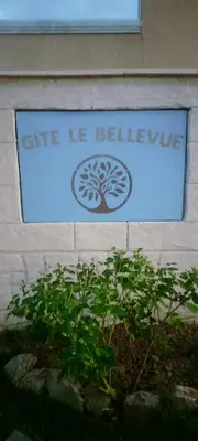 a sign on the side of a building with a tree at Gîte Le Bellevue in Montels