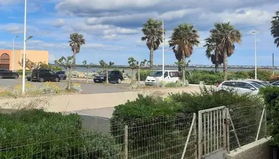 a parking lot with parked cars and palm trees at Appart RDC avec cour à 60 m plage du Grazel Gruissan in Gruissan