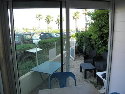 a patio with a table and chairs and a window at Appart RDC avec cour à 60 m plage du Grazel Gruissan in Gruissan