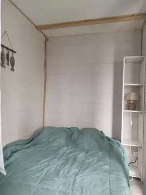a bed in a room with a white wall at Appart RDC avec cour à 60 m plage du Grazel Gruissan in Gruissan