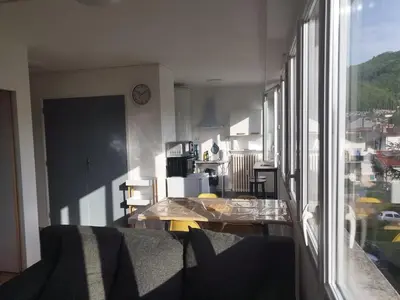 a living room with a table and a large window at Mistral gagnant ! T1 calme avec vue, parking, télétravail, Wi-Fi, proche CV et gare in Mazamet