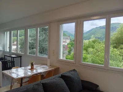 a room with a couch and a table and windows at Mistral gagnant ! T1 calme avec vue, parking, télétravail, Wi-Fi, proche CV et gare in Mazamet