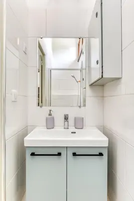 a white bathroom with a sink and a mirror at Appartement rez-de-chaussée Plage du Grazel in Gruissan