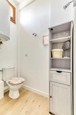 a white bathroom with a toilet and a shelf at Appartement rez-de-chaussée Plage du Grazel in Gruissan