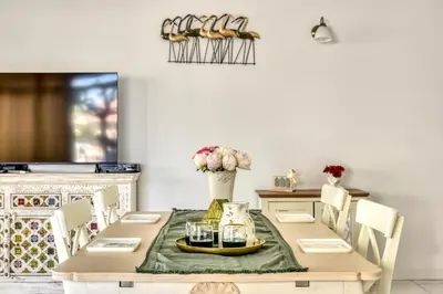 a dining room with a table with a green table runner at Appartement rez-de-chaussée Plage du Grazel in Gruissan