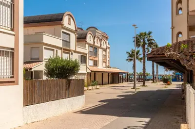 a street in a town with palm trees and buildings at Appartement rez-de-chaussée Plage du Grazel in Gruissan