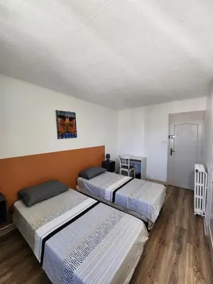 two beds in a room with white walls and wooden floors at Grand appartement vue sur la Cité ! in Carcassonne