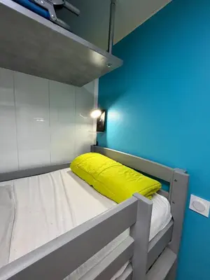 a bunk bed with a yellow pillow on top of it at Gruissan Plage Studio RDC avec Piscine Wifi Parking Clim in Gruissan