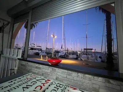 a window with a view of a marina with boats at Gruissan Plage Studio RDC avec Piscine Wifi Parking Clim in Gruissan