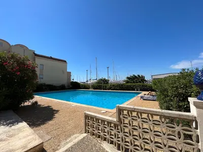 a swimming pool with a fence next to a building at Gruissan Plage Studio RDC avec Piscine Wifi Parking Clim in Gruissan