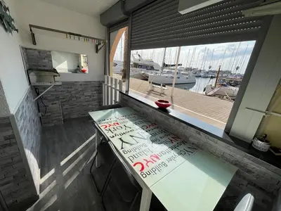 a table in a kitchen with a view of a marina at Gruissan Plage Studio RDC avec Piscine Wifi Parking Clim in Gruissan