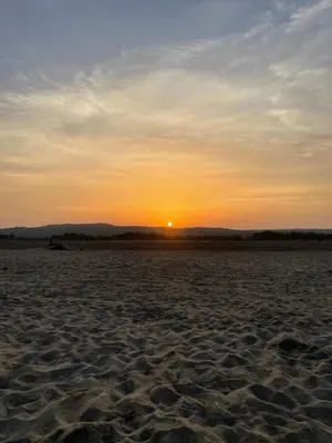 a sunset on a sandy beach with the sun in the distance at Chez Eugénia & Frédéric in Port-la-Nouvelle