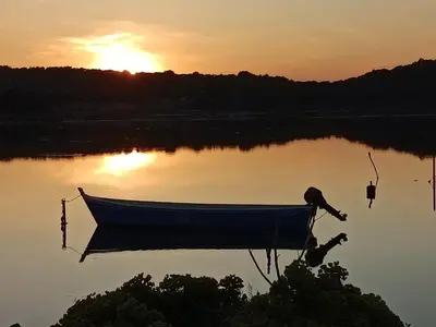 a boat sitting on a lake at sunset at le studio du Chat qui Pêche in Gruissan