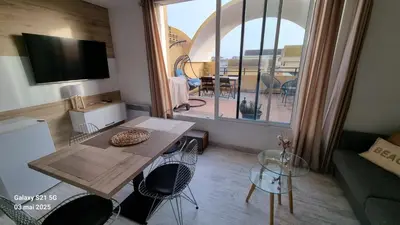 a living room with a table and a view of a balcony at Le Roof Top du Port, Nouveau, Bbq Duplex Clim Parking in Gruissan
