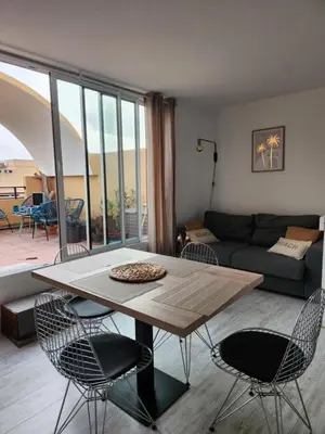 a living room with a table and chairs and a couch at Le Roof Top du Port, Nouveau, Bbq Duplex Clim Parking in Gruissan