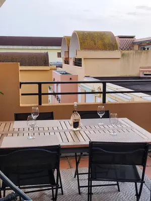 a table with two wine glasses on a balcony at Le Roof Top du Port, Nouveau, Bbq Duplex Clim Parking in Gruissan