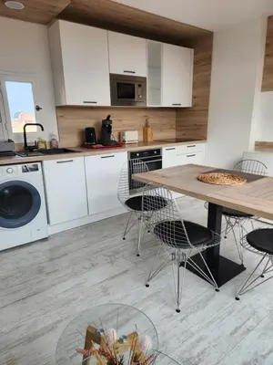 a kitchen with white cabinets and a table and chairs at Le Roof Top du Port, Nouveau, Bbq Duplex Clim Parking in Gruissan