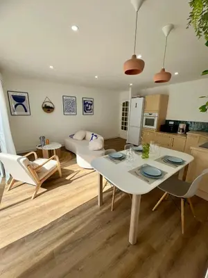 a kitchen and living room with a white table and chairs at Casa Dolorès parking, jardin, Gds Buffets 10 min in Narbonne