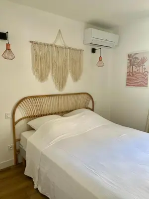 a bedroom with a bed with white sheets and a fan at Casa Dolorès parking, jardin, Gds Buffets 10 min in Narbonne
