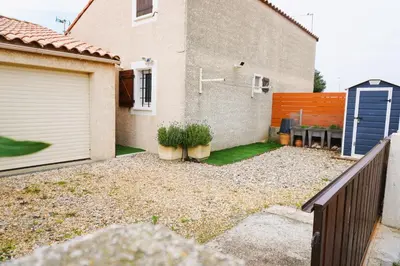 a backyard with a house and a blue door at Le Lagon Clim Parking 4Pers in Port-la-Nouvelle
