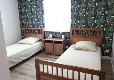 two twin beds in a room with floral wallpaper at Le Patio in Castelnaudary