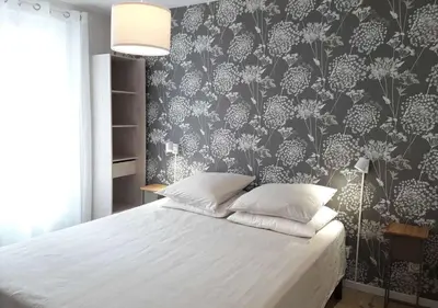 a bedroom with a white bed with a floral wallpaper at Le Patio in Castelnaudary