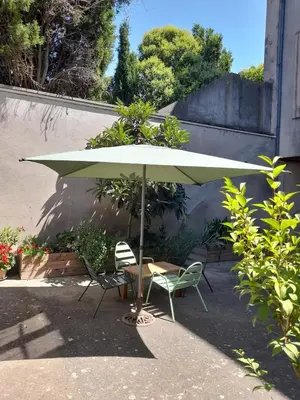 a table and two chairs under a green umbrella at Le Patio in Castelnaudary