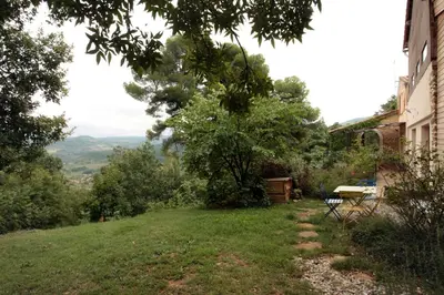 a grassy yard with a bench on the side of a house at Gite rural de Bergnes à l'ombre des grands pins in Campagne-sur-Aude