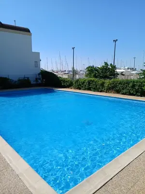 a large blue swimming pool next to a building at Charming studio with sea view Gruissan in Gruissan